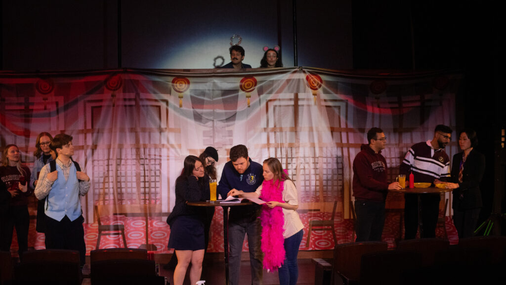 Actors huddled around a table on stage.