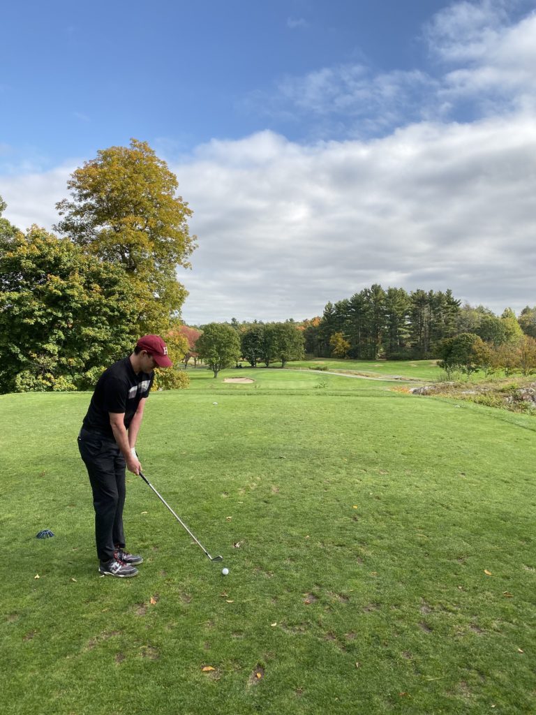 Person teeing up a swing.