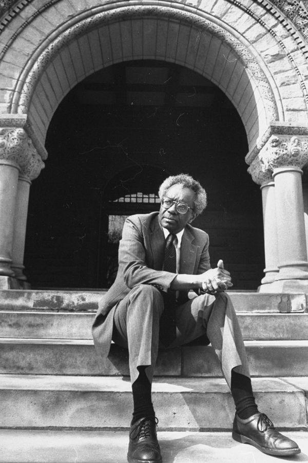Derrick Bell sitting on the steps of Austin Hall at Harvard Law School, April 1990.